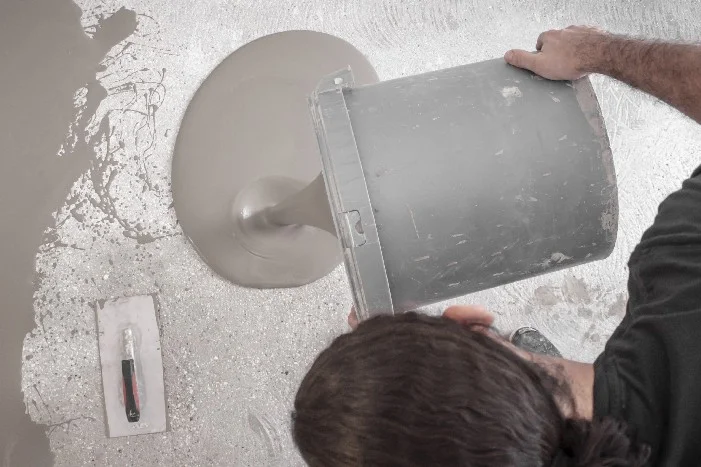 Person gießt Estrich auf Boden